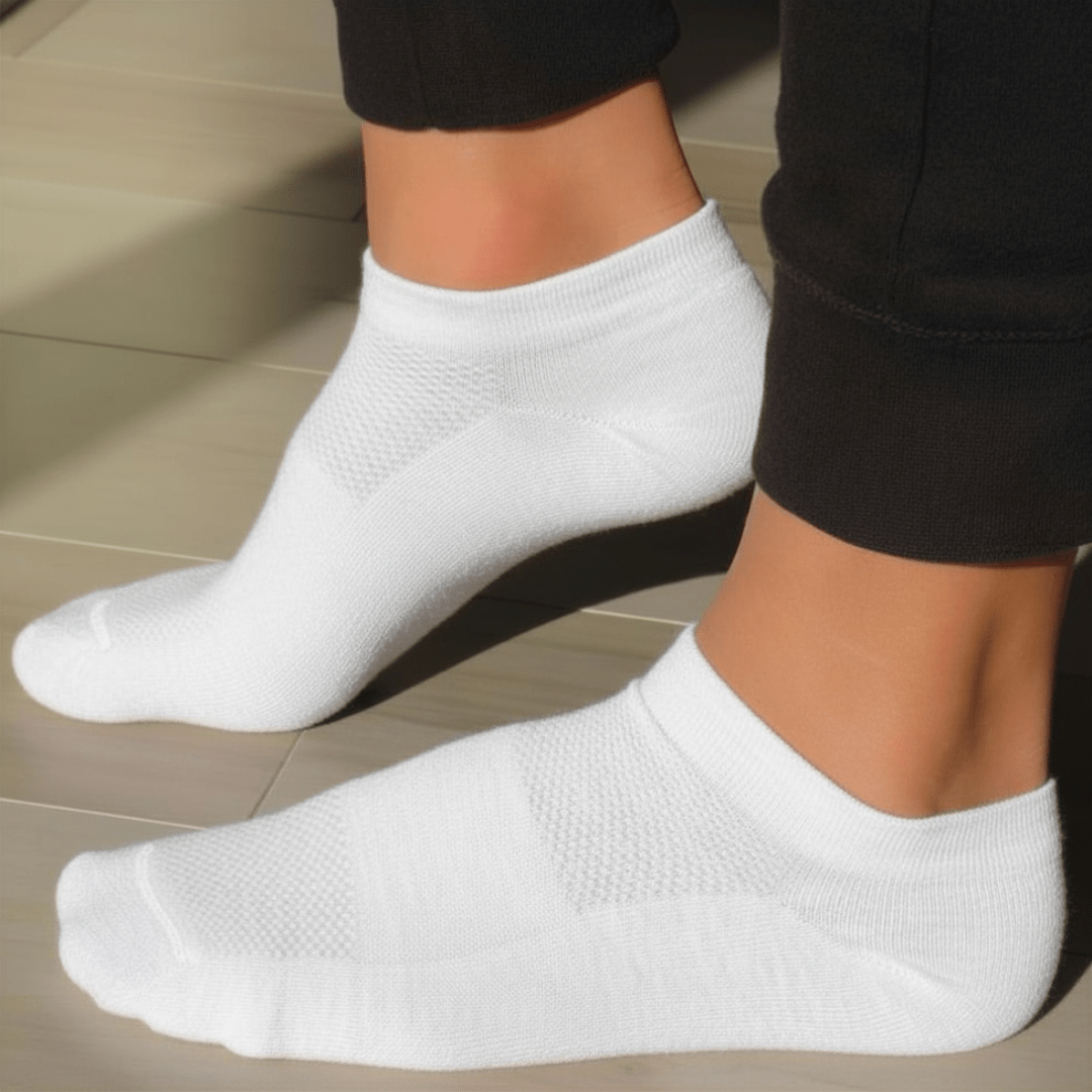 A lifestyle pic of white YoU Compression Ankle Socks being worn. Shows a low-cut fit of 20-30 mmHg socks and black joggers.